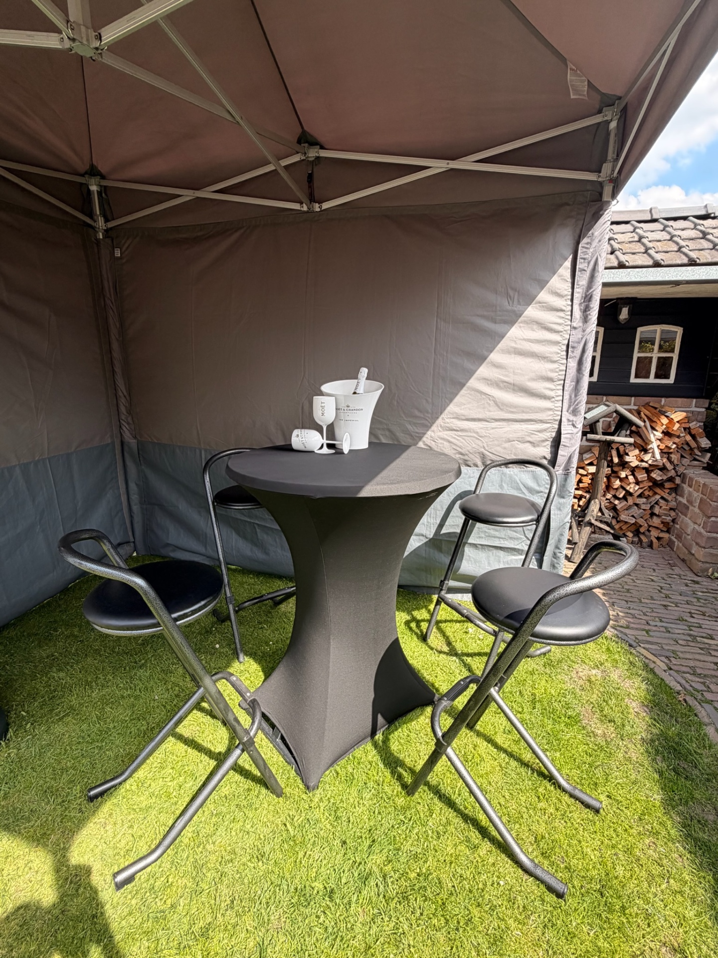Statafel met zwarte rok en barkrukken onder easy-up tent